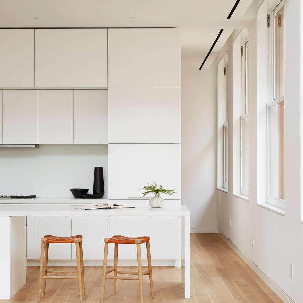 آشپزخانه کوچک مدرن با رنگ بندی سفید و قهوه ای روشن و صندلی های نارنجی و قهوه ای