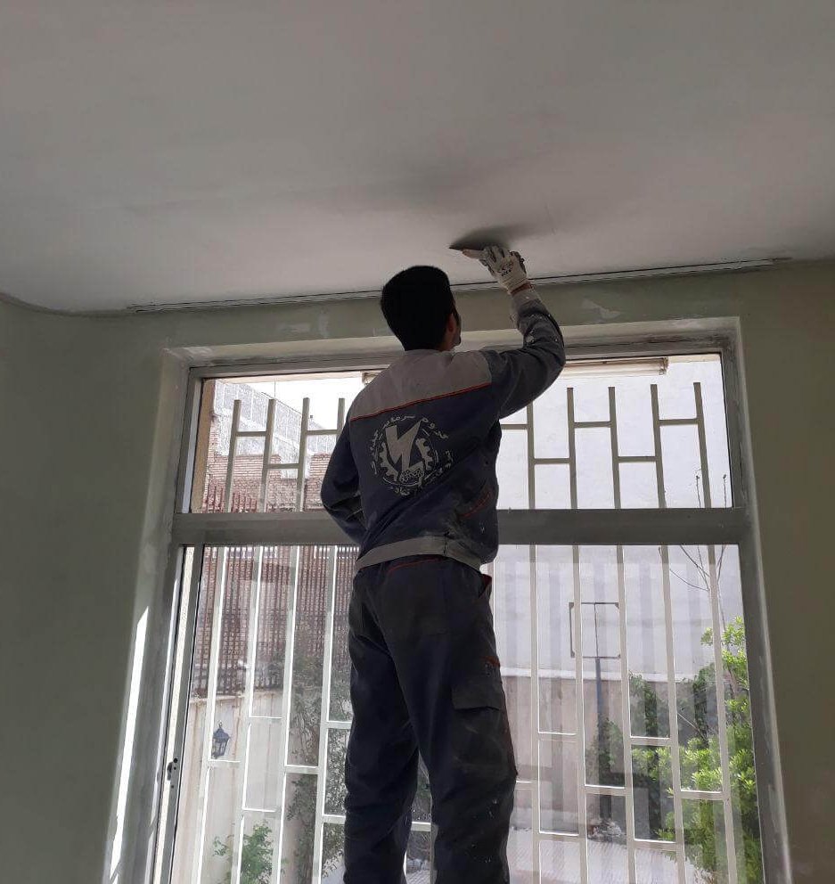 نقاشی و بتونه کاری سقف قبل از رنگ آمیزی اتاق با رنگ پلاستیک سفید