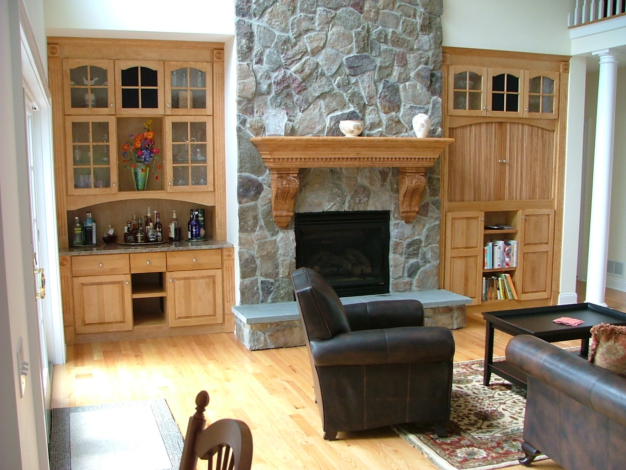 دو مدل کمد دکوری چوبی قهوه ای در دو طرف شومینه به شکل قرینه در پذیرایی خانه