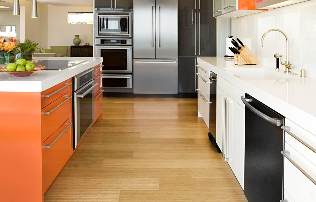 کفپوش چوبی قهوه‌ای روشن در آشپزخانه مدرن با کابینت سفید و نارنجی