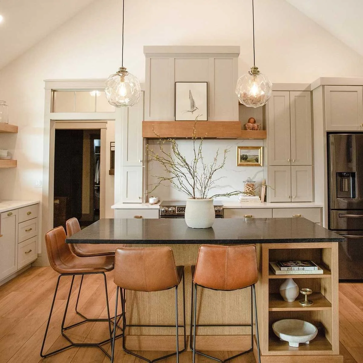 آشپزخانه با کابینت‌های روشن و کانتر چوبی با صندلی‌های چرمی عسلی رنگ