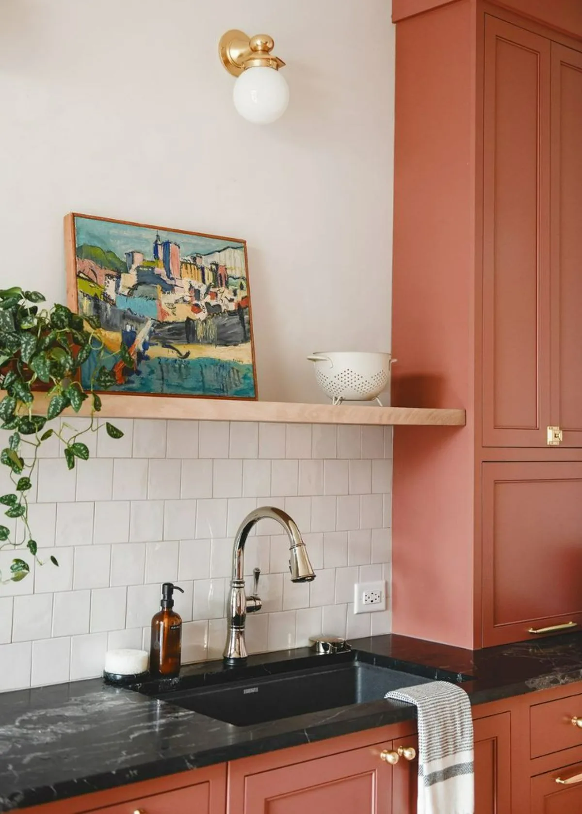 آشپزخانه با قفسه هلویی ملایم که روی آن قاب نقاشی و گلدان قرار دارد