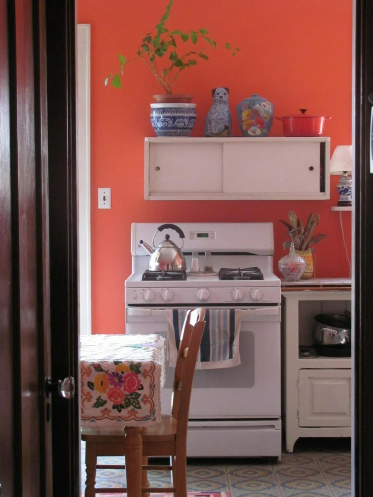 آشپزخانه با دیوار هلویی رنگ همراه با اجاق گاز و کابینت سفید