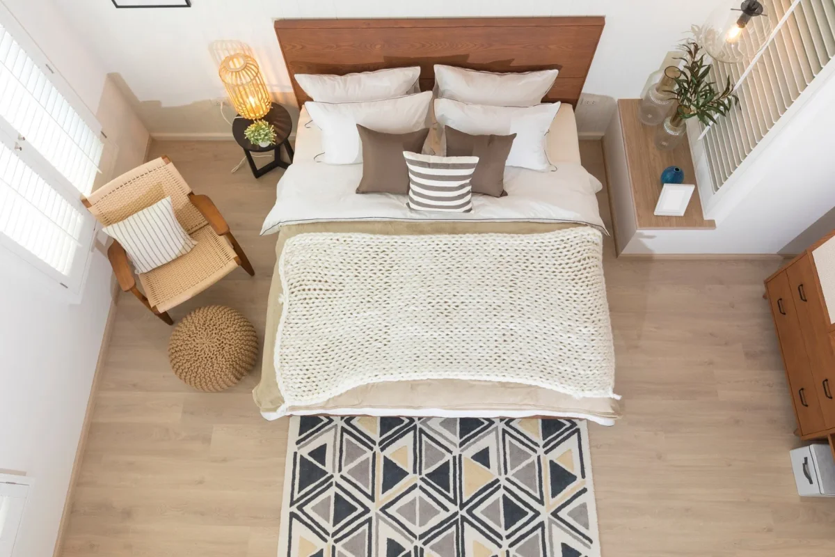 اتاق خواب با کف‌پوش چوبی روشن و فرش کوچک طوسی و سرمه‌ای